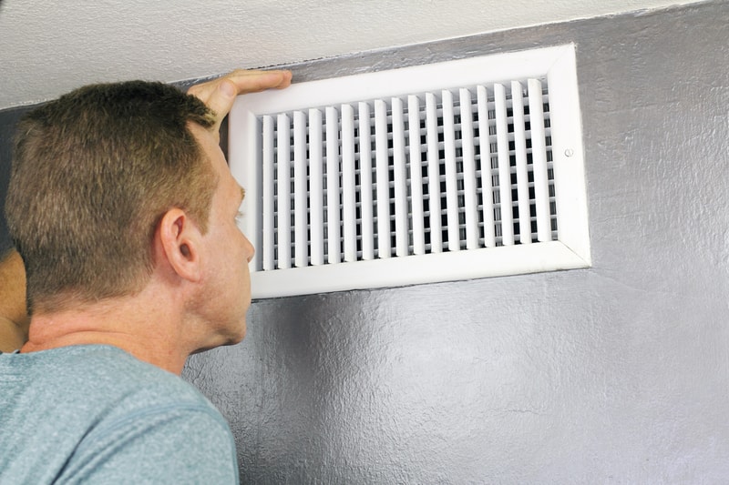 man looking into air duct